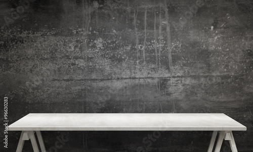 Modern white table with legs and free space. Black wall texture in background. photo