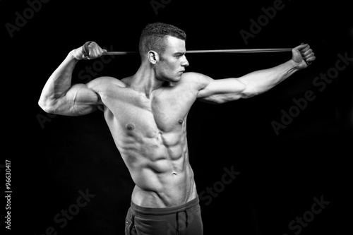 Muscular fitness man presents his body building on black background