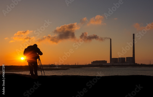 photographer at sunrise on the coast, on a background of pipes p