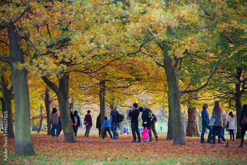 LONDON, UK - OCTOBER 31, 2015: Autumn in London park, people and families walking and enjoying the weather photo