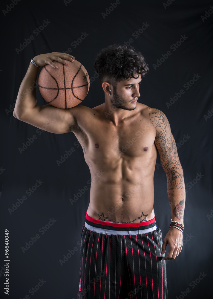 Young athletic man on dark background holding basketball ball Young athletic man on dark background holding basketball ball