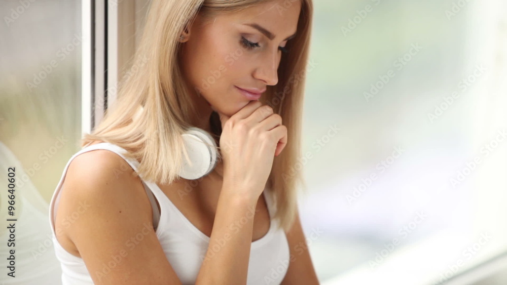 Pretty girl sitting by window using laptop looking at camera and smiling. Panning camera Pretty girl sitting by window using laptop looking at camera and smiling. Panning camera