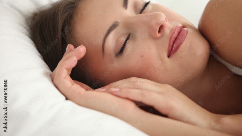 Attractive girl sleeping in bed waking up looking at camera and smiling. Panning camera Attractive girl sleeping in bed waking up looking at camera and smiling. Panning camera
