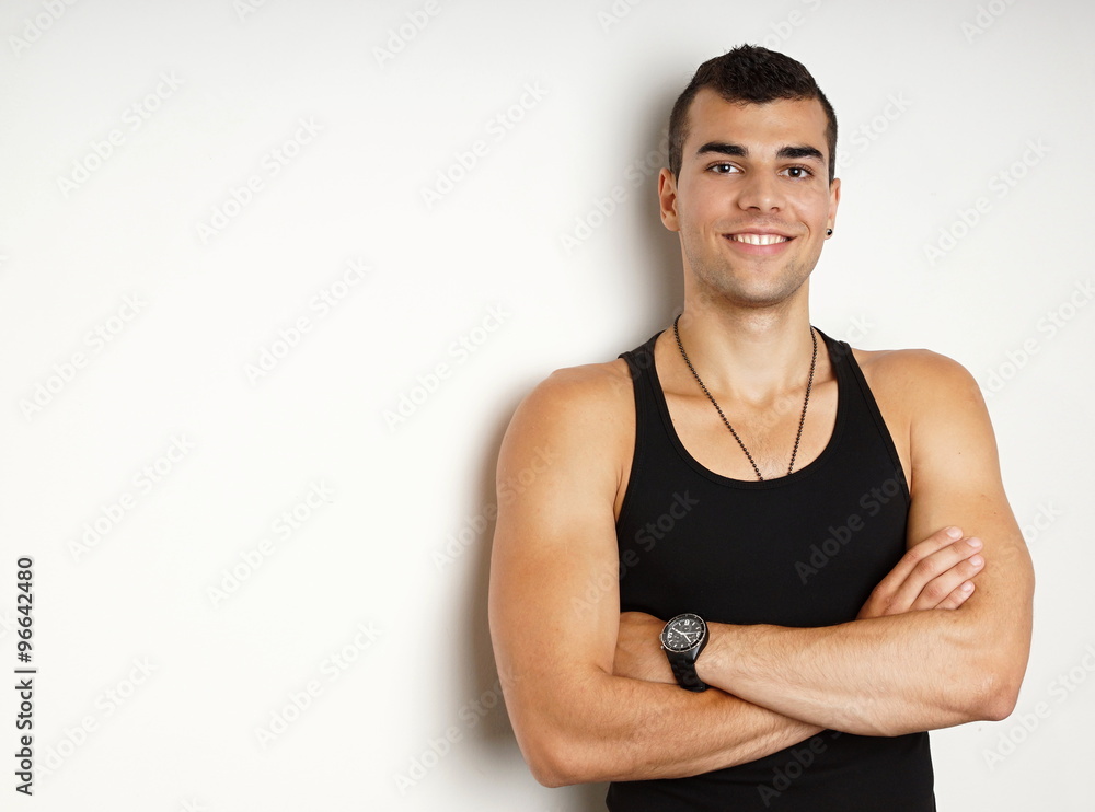 Young man in black undershirt leaning against the wall, left you can write some text Young man in black undershirt leaning against the wall, left you can write some text