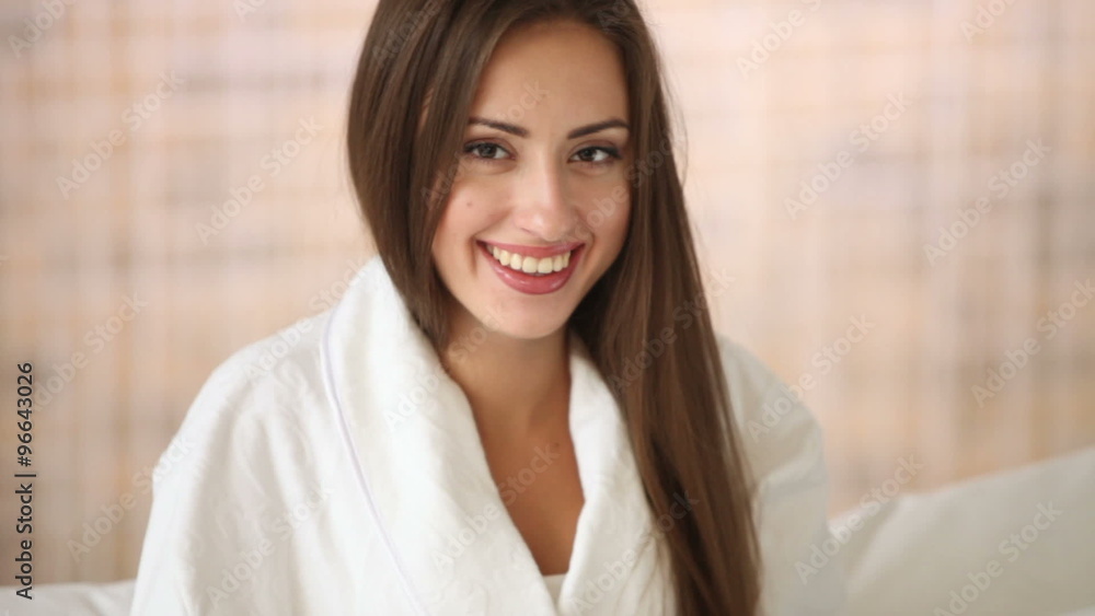 Cute young woman relaxing in bed using laptop looking at camera and smiling. Panning camera Cute young woman relaxing in bed using laptop looking at camera and smiling. Panning camera