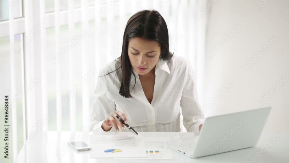 Pretty young woman sitting at office desk working using laptop looking at camera and smiling Pretty young woman sitting at office desk working using laptop looking at camera and smiling