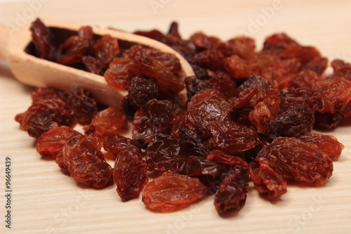 Brown raisins with spoon on wooden table, healthy eating