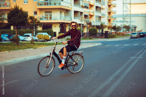 Man in sunglasses riding a bike on city street