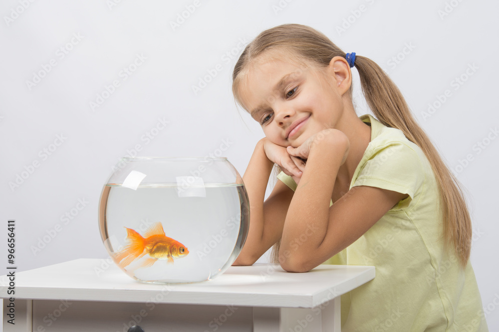 Thoughtful girl dreaming and looking at goldfish Thoughtful girl dreaming and looking at goldfish