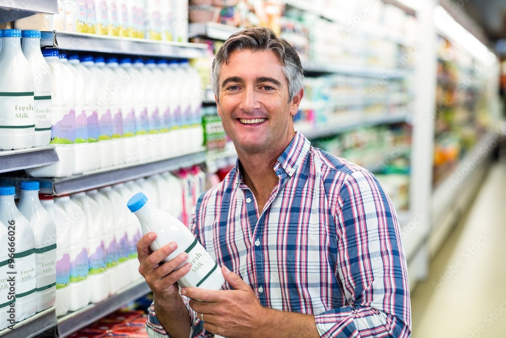 Smiling man holding milk bottle