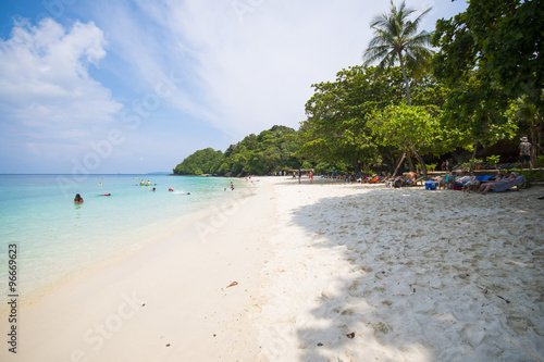 Tourists enjoy swimming and sunbathing on the beach