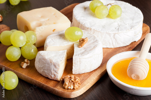 cheeses, grapes and walnuts on a wooden background, horizontal