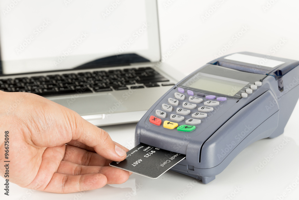 Hand Swiping Credit Card With Laptop In Background Hand Swiping Credit Card With Laptop In Background