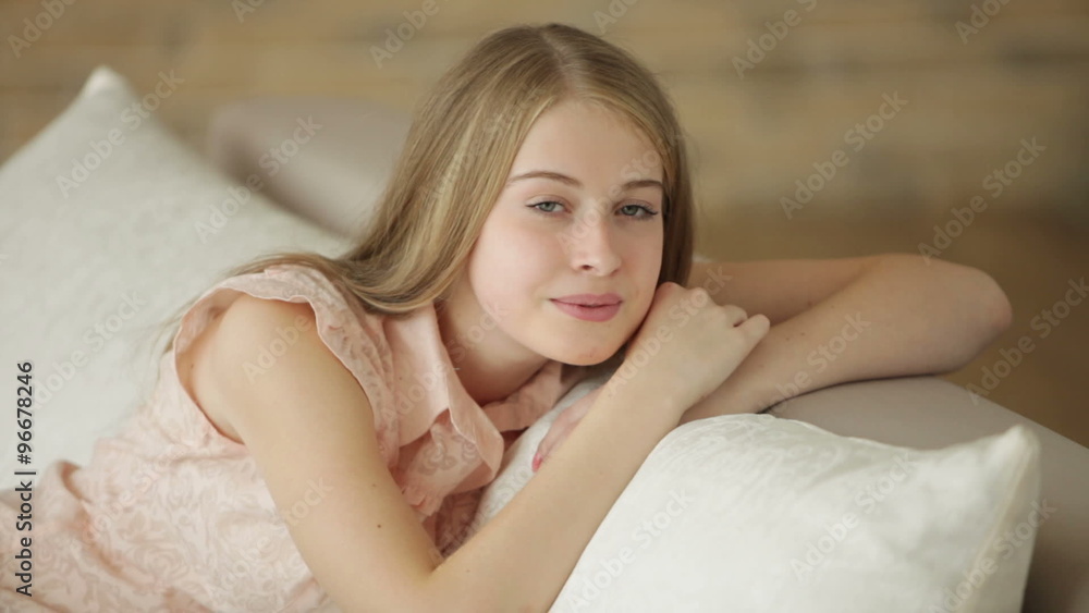 Charming young woman relaxing on couch looking at camera and smiling. Panning camera Charming young woman relaxing on couch looking at camera and smiling. Panning camera