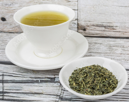 Japanese green tea in white cup over wooden background