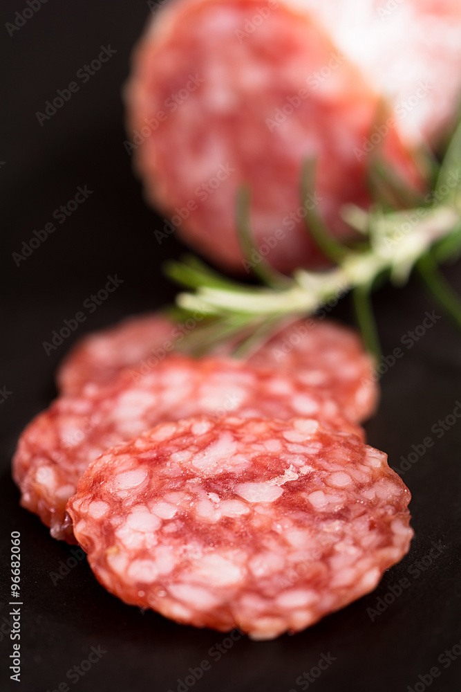Salamischeiben mit einer Salami im Hintergrund Salamischeiben mit einer Salami im Hintergrund