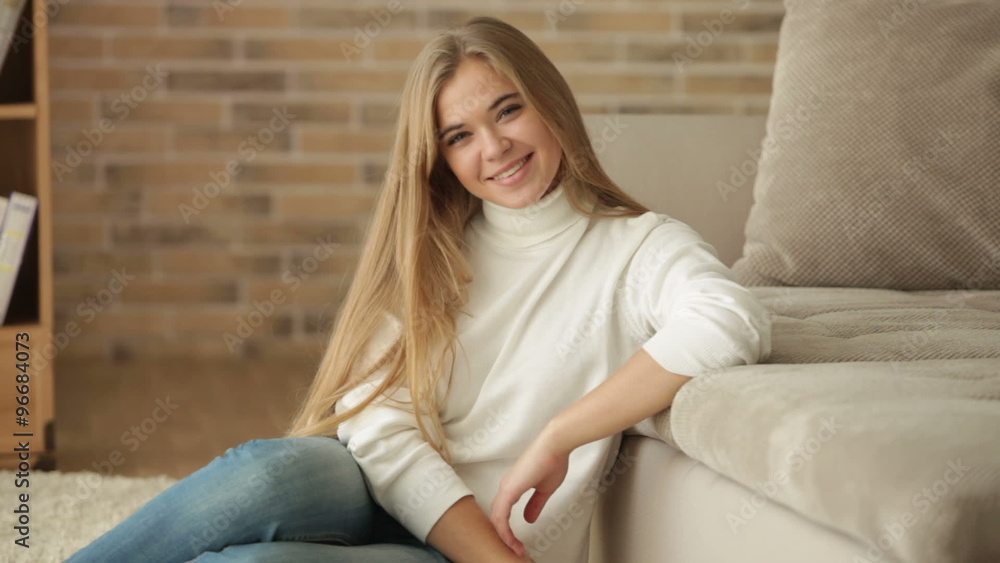 Charming girl sitting on floor looking at camera and smiling. Panning camera Charming girl sitting on floor looking at camera and smiling. Panning camera