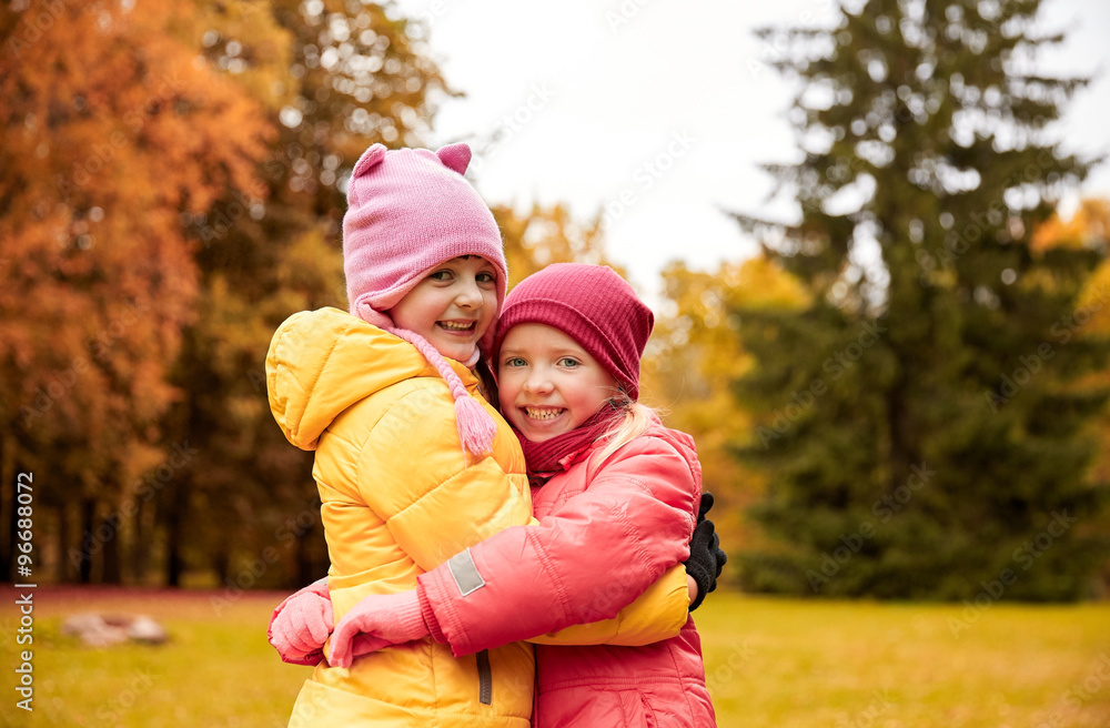 two happy little girls hugging in autumn park