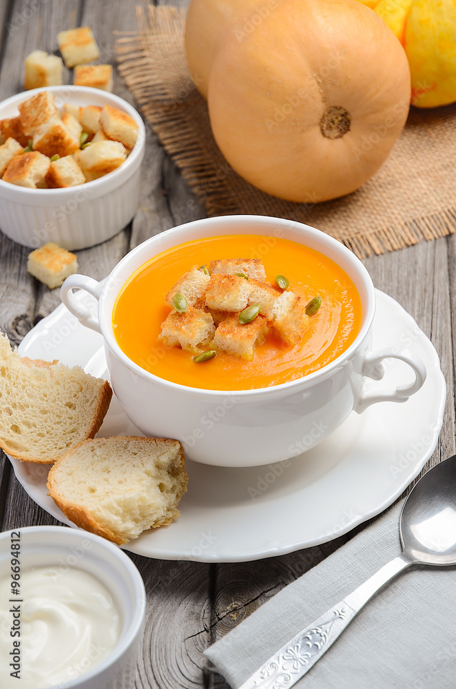 Pumpkin soup with pumpkin seeds and croutons on the rustic wooden table Pumpkin soup with pumpkin seeds and croutons on the rustic wooden table