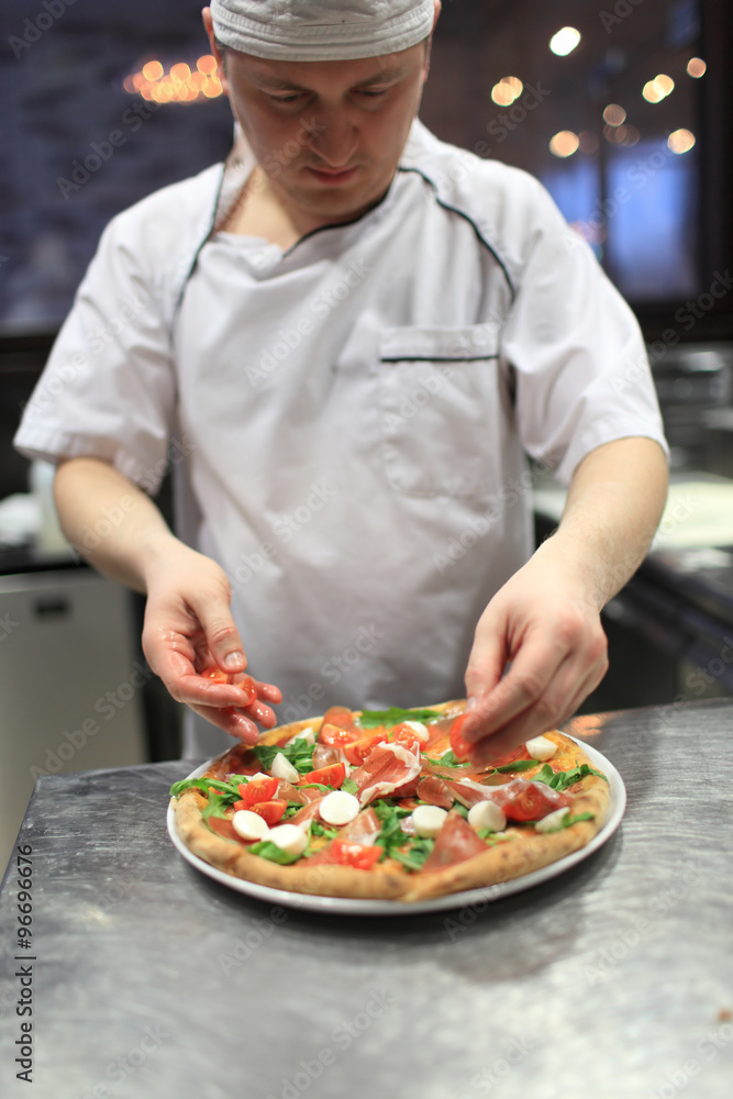 chef baker in white uniform making pizza at kitchen.Focus on the pizza