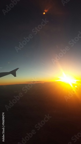 Skrzydło samolotu przy zachodzie słońca w chmurach