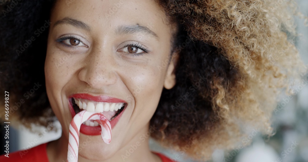 Fun young woman biting Christmas candy cane Fun young woman biting Christmas candy cane