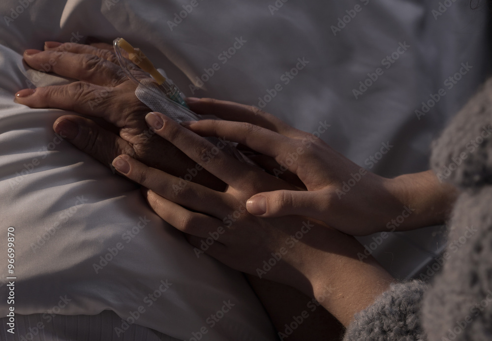 Woman holding ill mother hand