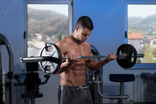 Man In The Gym Exercising Biceps With Barbell