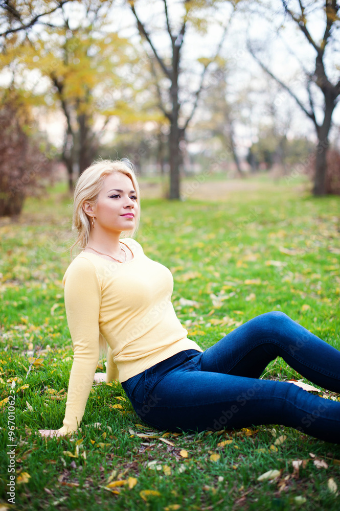 Young beautiful woman sitting on grass looking away Young beautiful woman sitting on grass looking away