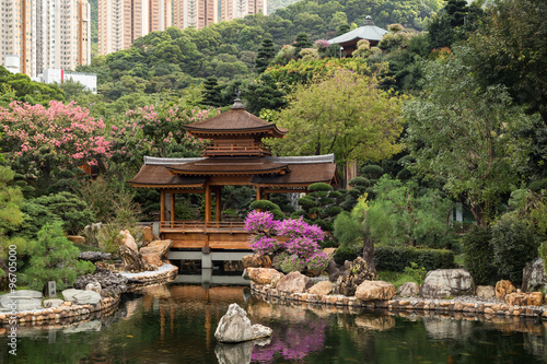Traditional wooden bridge by the pond at the Nan Lian Garden in Hong Kong, China. High-rise apartment buildings in the background.