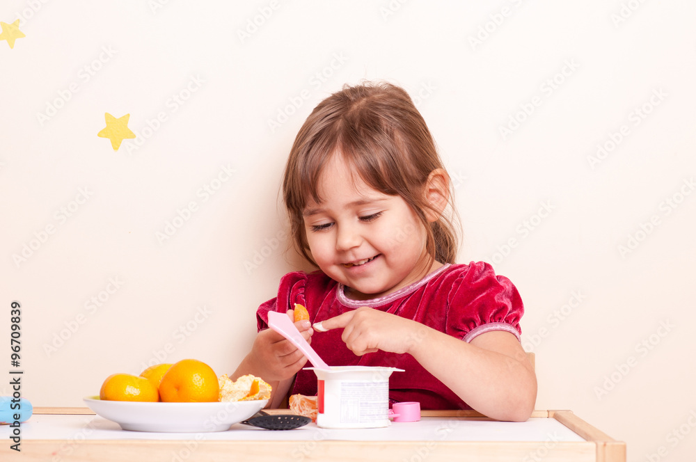 happy smiling little girl eating fruits and yogurt