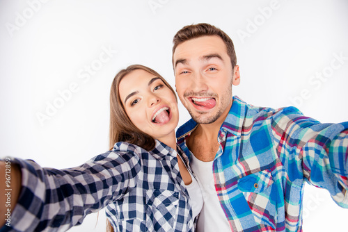 Cheerful funny couple in love making selfie photo showing tongue © deagreez