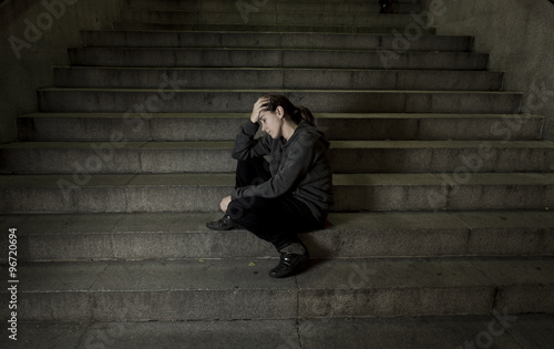 sad woman alone on street subway staircase suffering depression looking looking sick and helpless