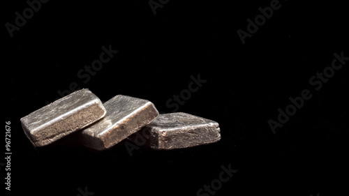 Fototapeta Naklejka Na Ścianę i Meble -  Three silver ore bars stacked in a row photographed against a black background.