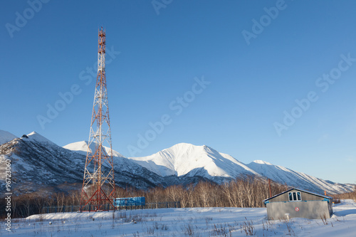 Telecommunication tower with a clear blue sky on the snowy valley