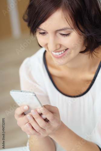 lächelnde frau liest eine nachricht auf ihrem smartphone