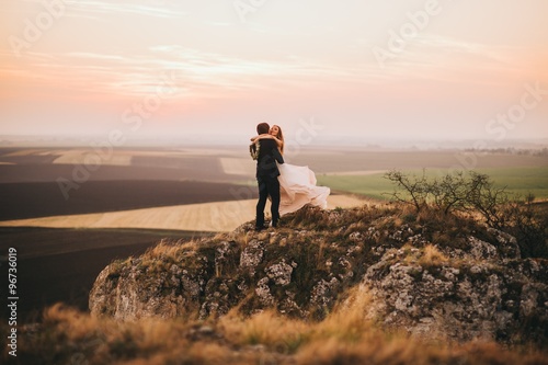 Wedding couple looking in mountain hill on sunset
