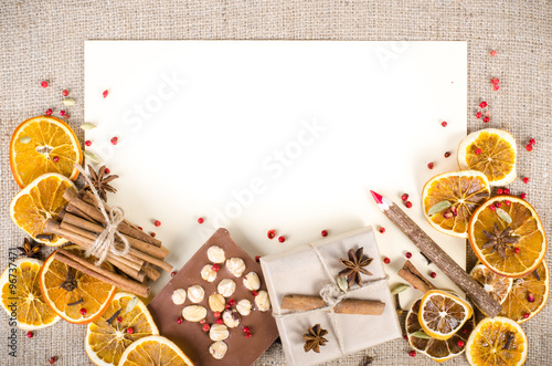 Dried oranges, cinnamon, cloves, cardamom, handmade milk chocolate with nuts, wooden pencil, list of paper on sackcloth, canvas. Christmas, New Year and winter. Free space for your text. photo