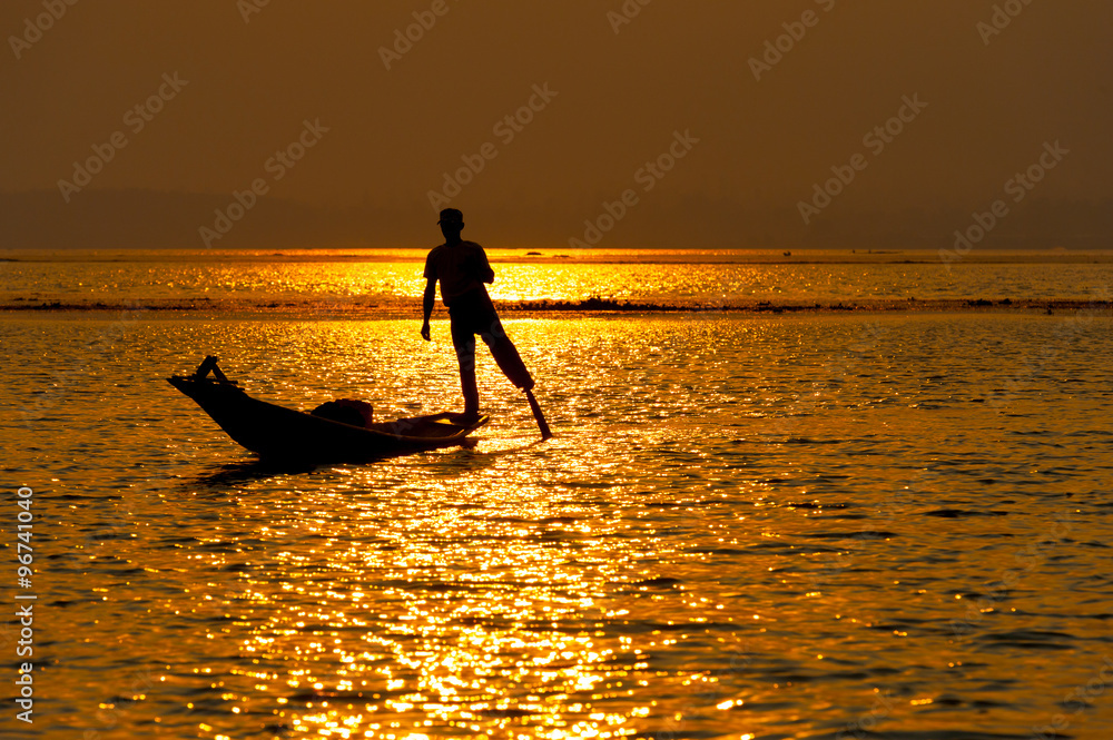 INLE LAKE VILLAGE MYANMAR : Silhouette People rows the wooden boat by his leg in Inle Lake