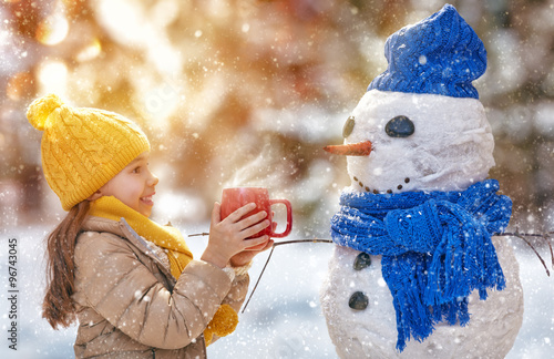 girl playing with a snowman photo