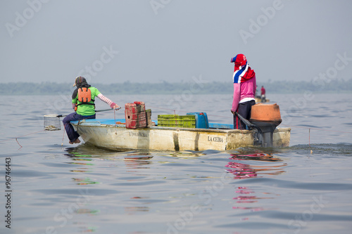 Two fisher men on a small wooden boat at work looking for crabs on the lake of Maracaibo. Famous for its crab fisheries with increasing production. Venezuela 2015 photo