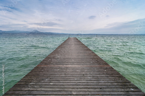 Fototapeta Naklejka Na Ścianę i Meble -  wooden pier and cloudy sky over Garda lake - Italy