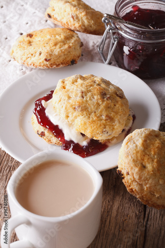 English pastries: scones with jam and tea with milk close-up. vertical
 photo