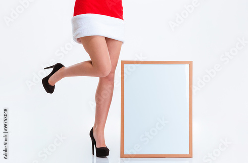 Female legs in santa claus cloth and blank board