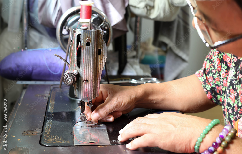 Woman hand threading needle into sewing machine needle