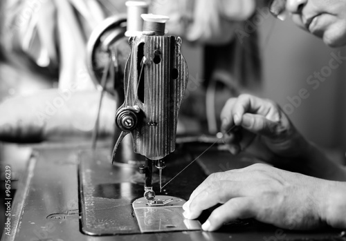 Obraz na plátne Woman hand threading needle into sewing machine needle