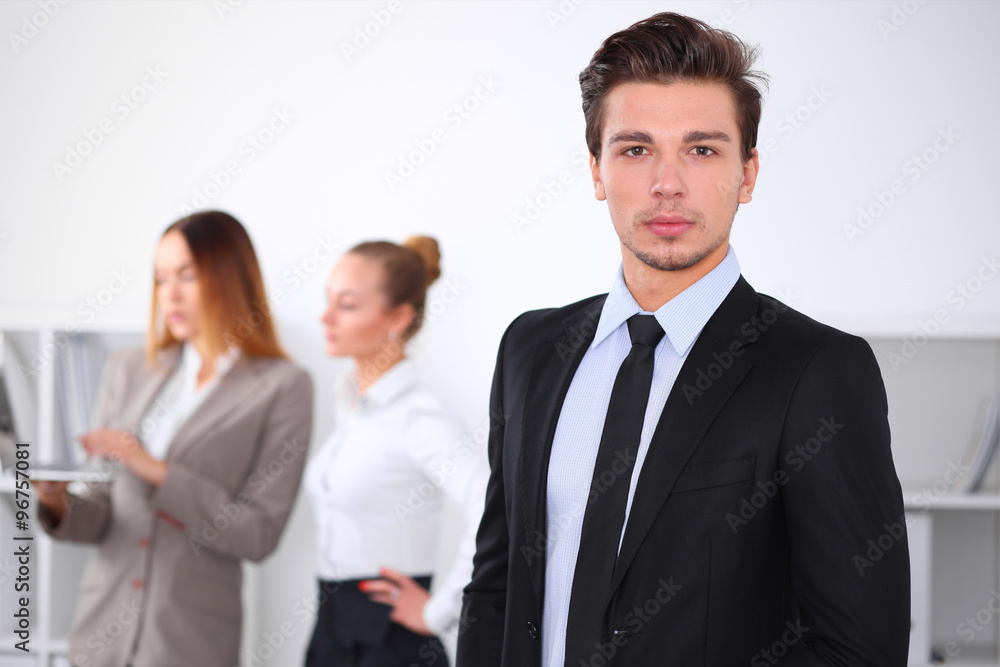 Cheerful business man in office with colleagues in the background, sturt up team Cheerful business man in office with colleagues in the background, sturt up team
