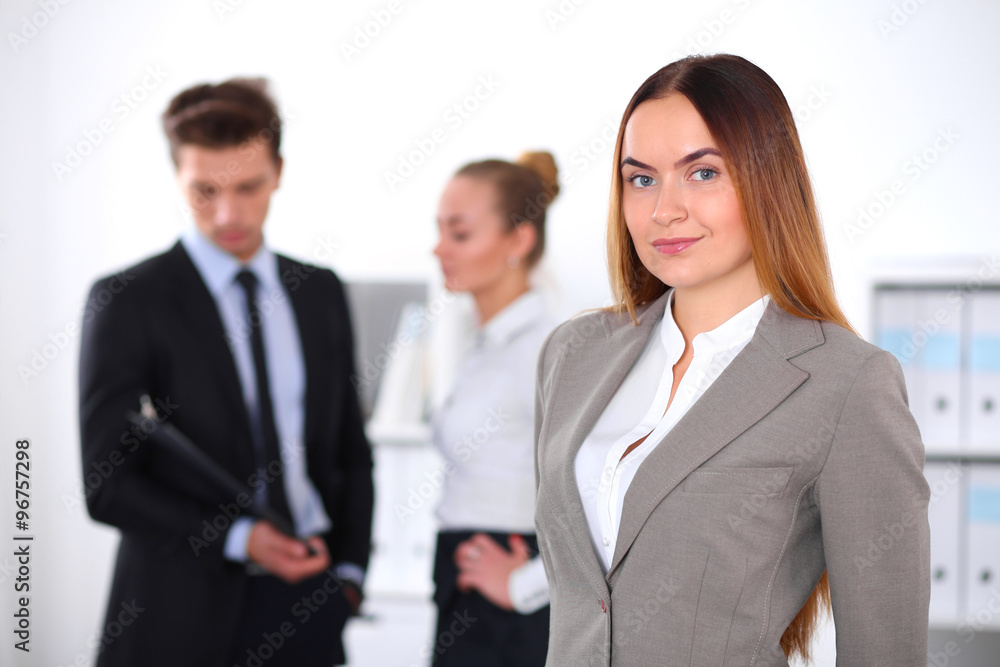 Pretty businesswoman in office with colleagues in the background Pretty businesswoman in office with colleagues in the background