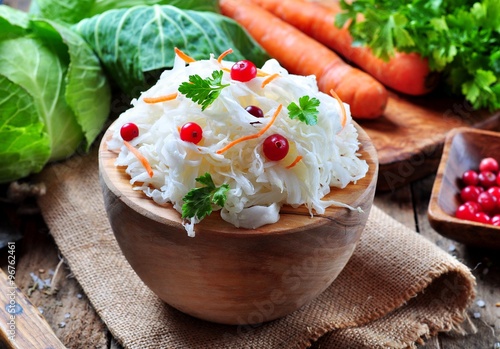 sauerkraut with cranberries and carrots in a wooden bowl on a wooden background. rustic style. Selective focus.