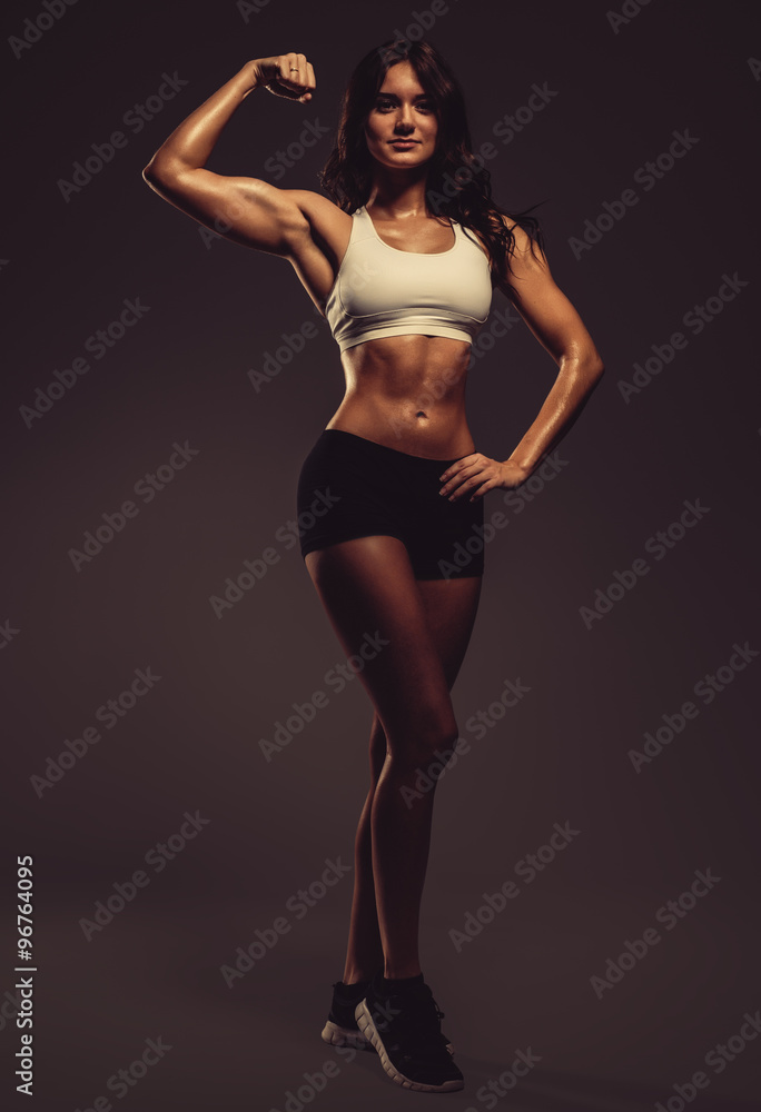 Beautiful young athletic woman showing biceps